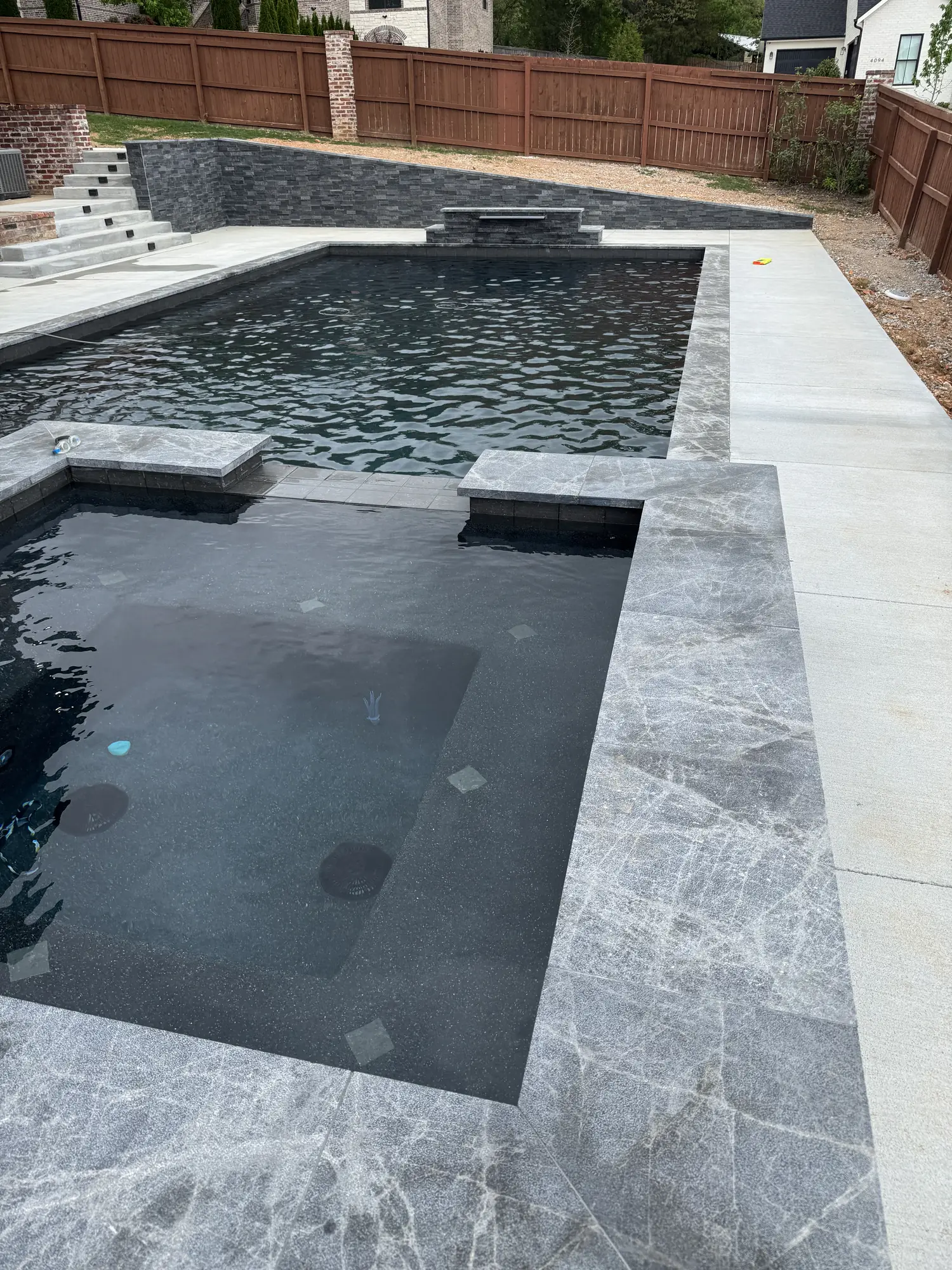 Black-bottom pool and raised spa with marble deck in Northwest Arkansas