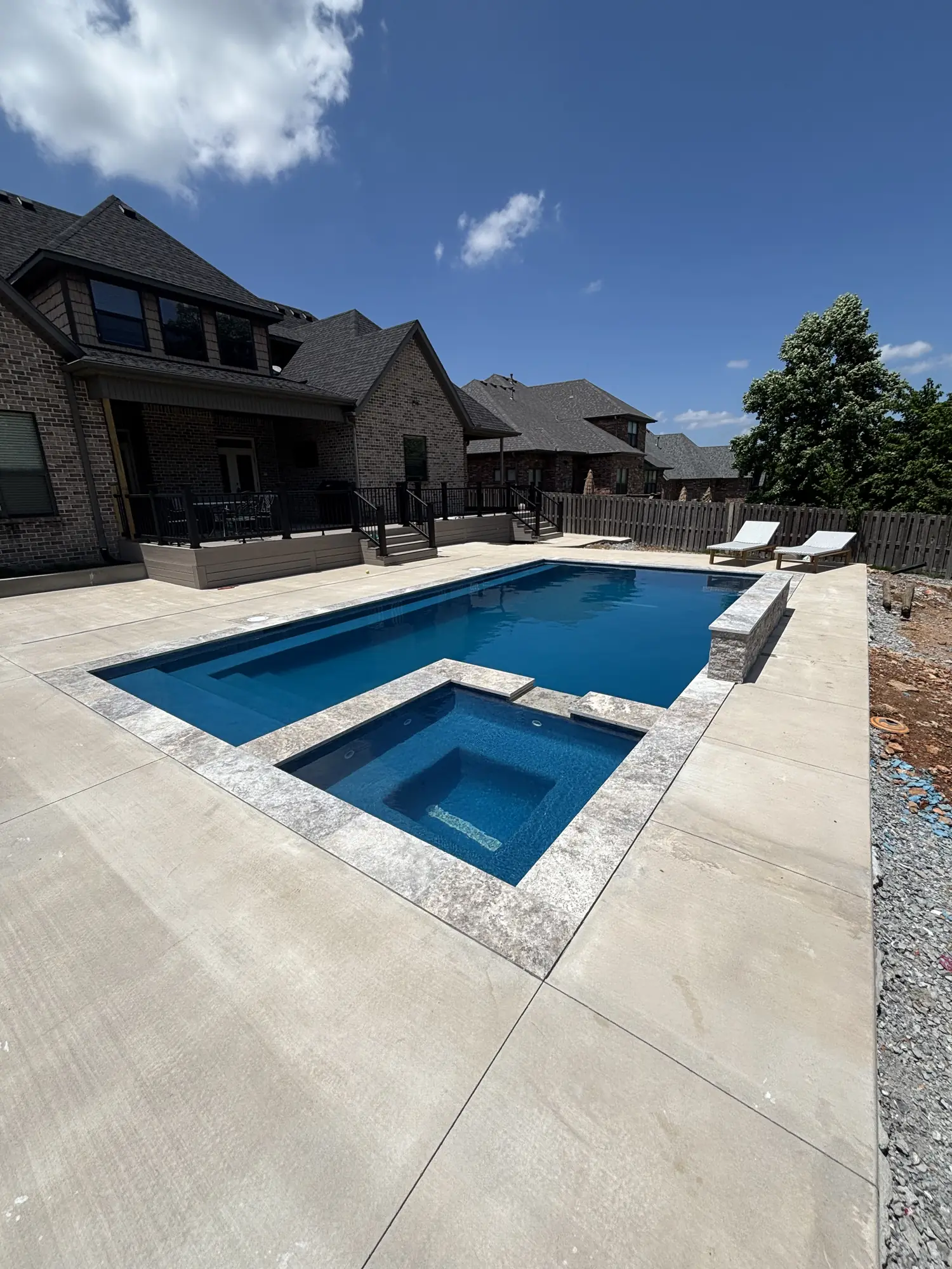 Modern pool and spa with travertine deck at a brick home in Northwest Arkansas