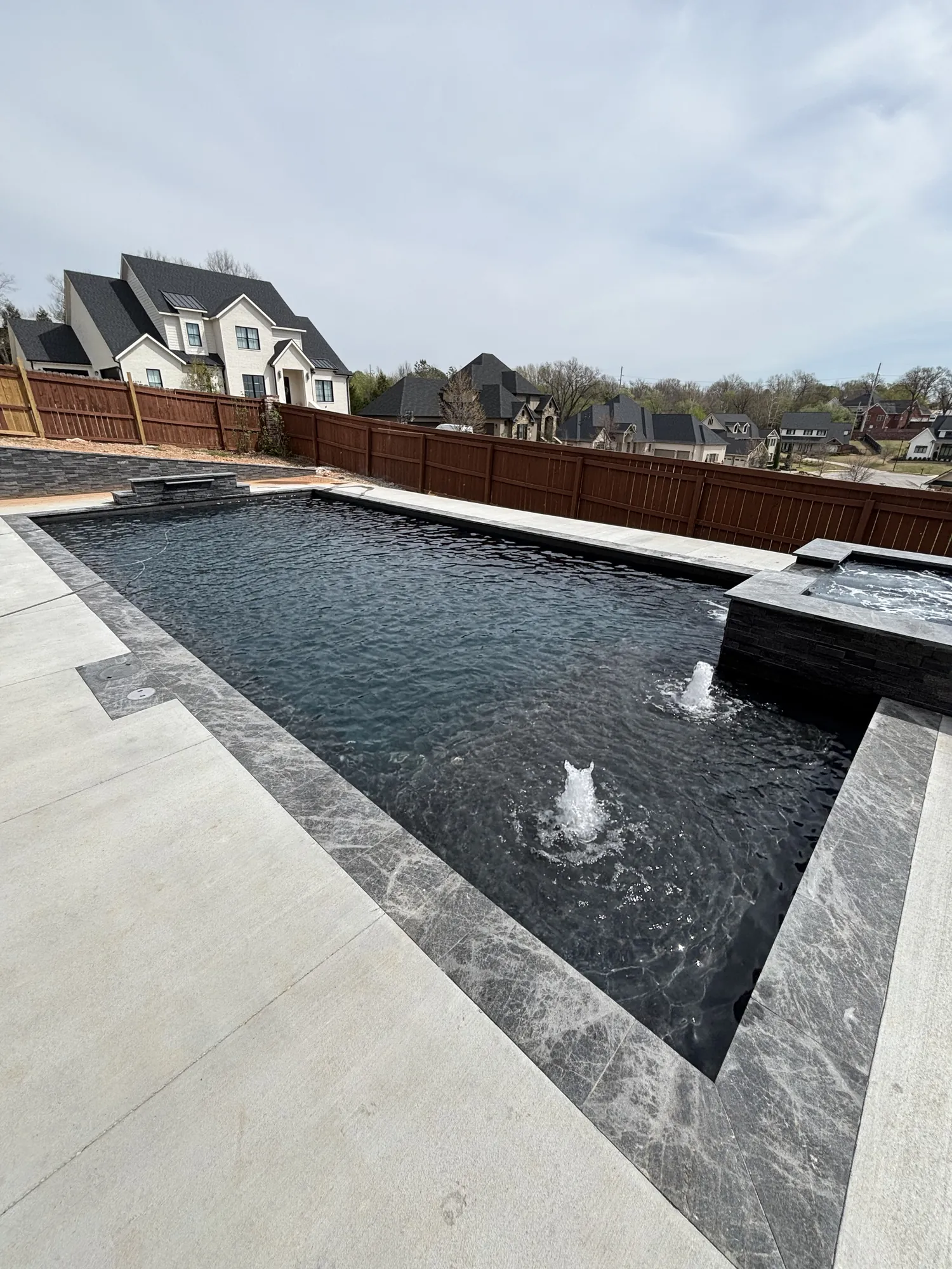 Modern pool with raised spa and marble coping in Northwest Arkansas
