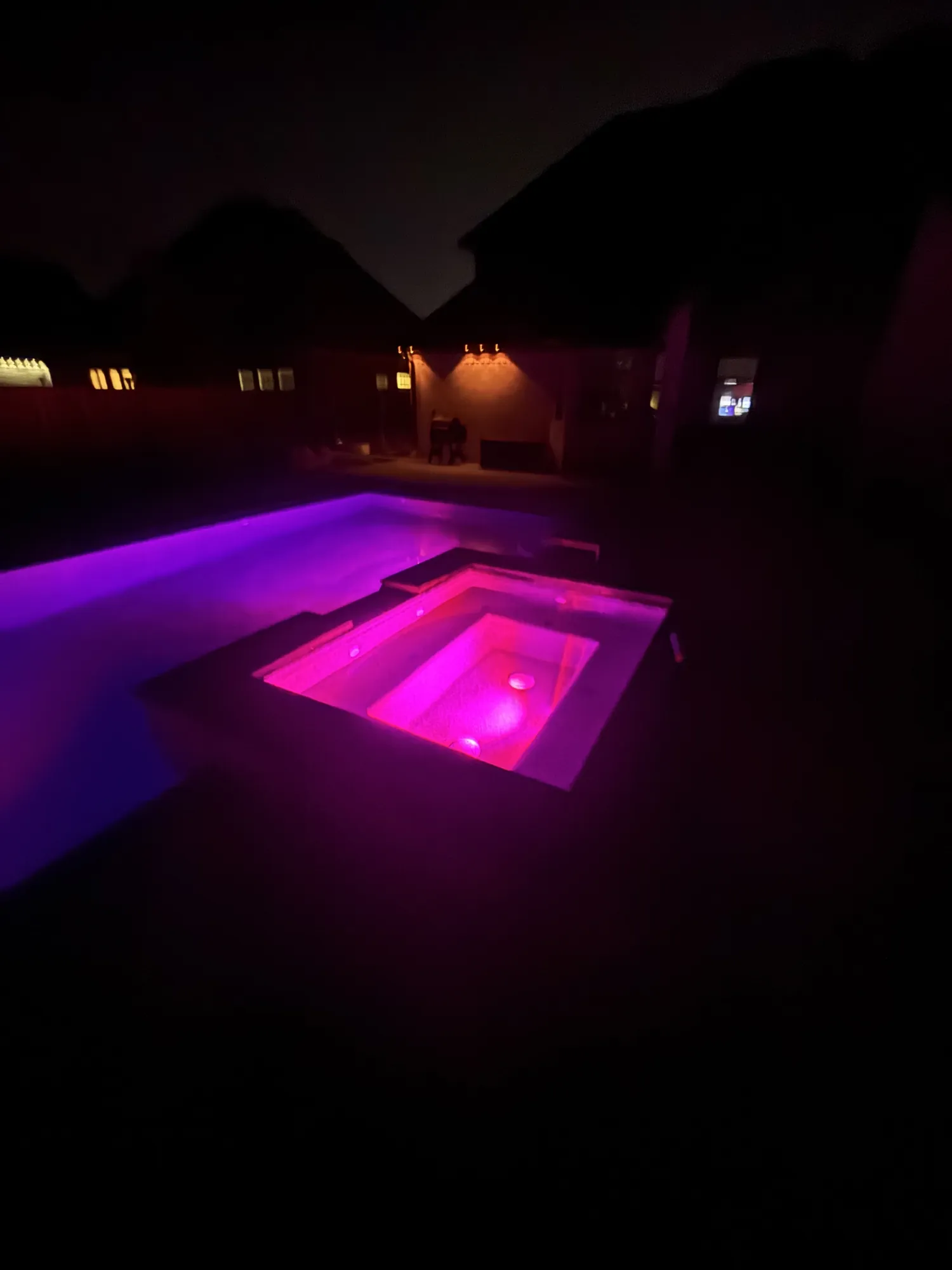 Pool and spa with color-changing LED lighting at night in Northwest Arkansas