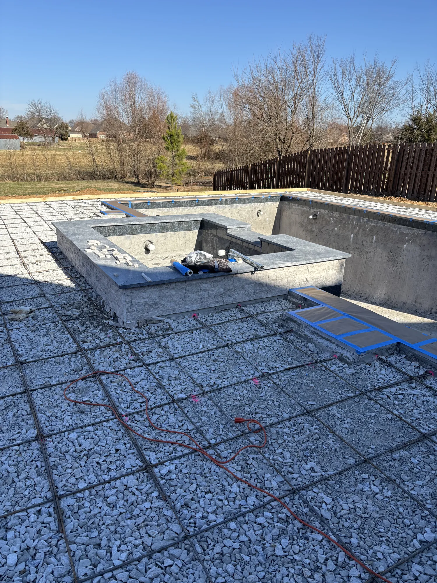 Pool and spa with freshly installed pebble decking in Northwest Arkansas