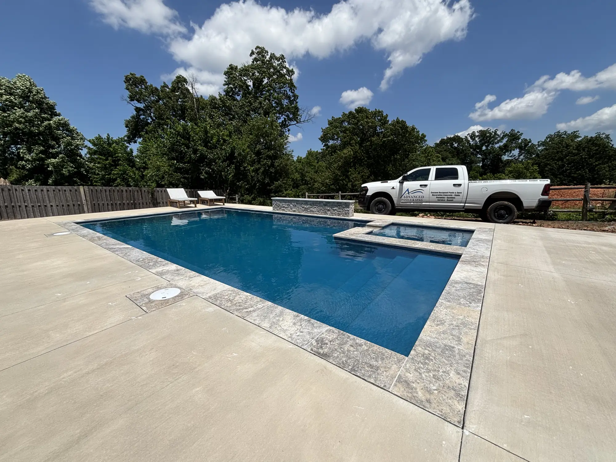Rectangular pool and raised spa with travertine coping in Northwest Arkansas
